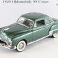 A green vintage die-cast model car with chrome details and white-walled tires, photographed against a plain white background with text partially visible above.