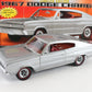 A silver die-cast model car of a 1967 Dodge Charger with red interior and black-and-red wheels, shown in front of its original orange and red packaging box.