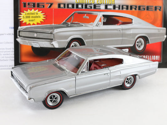A silver die-cast model car of a 1967 Dodge Charger with red interior and black-and-red wheels, shown in front of its original orange and red packaging box.