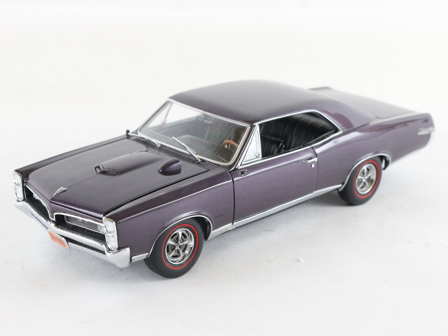 A purple die-cast model car of a classic muscle car, photographed on a clean white background.