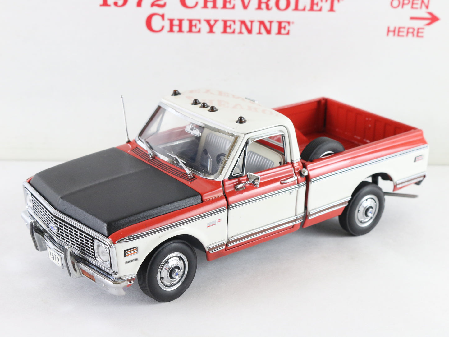A 1972 Chevrolet Cheyenne model truck, likely a diecast scale model, shown from a three-quarter front angle. The truck features a white body WITH red, roof, and bed, and a black hood.